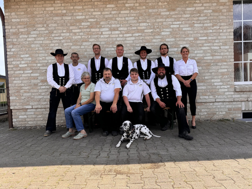 Teamfoto vor eine Hausfassade mit einem Hund im Vordergrund